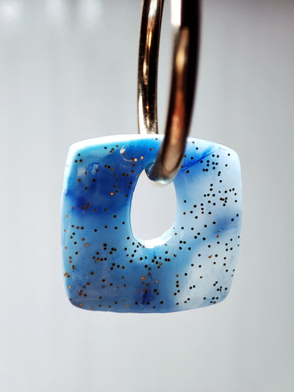 boucles d'oreilles modulables carrées bleu minéral doré pailleté gros plan par transparence